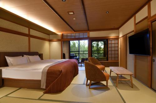a bedroom with a bed and a flat screen tv at Yunogo Onsen HOTEL YUNOMORI BISYUNKAKU in Mimasaka