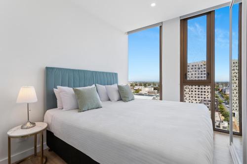 a bedroom with a large white bed and a large window at The Cullinan Apartments by CLLIX in Adelaide
