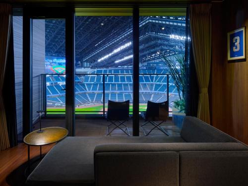 a living room with a couch and a view of a stadium at tower eleven hotel in Kitahiroshima