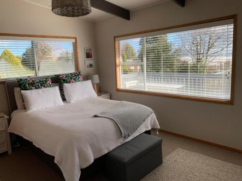 a bedroom with a bed and two large windows at Lake Views, Ani Miria Place, Te Rangiita, Turangi in Turangi
