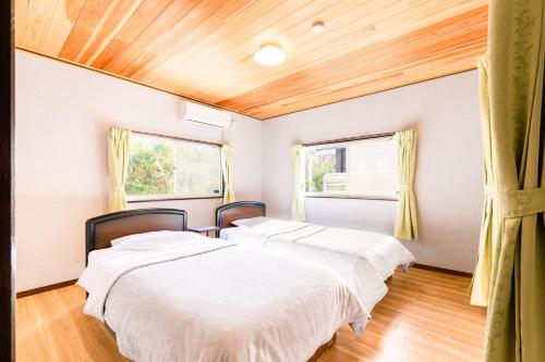 two beds in a room with two windows at ウッドペッカーC棟BBQPetりんどう湖近くの一棟貸別荘 in Nasu