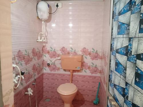 a bathroom with a toilet and pink flowers on the wall at Holiday Homestay Beach Rooms Deep Diving & Light House & Watersports Tarkarli in Bhogwe