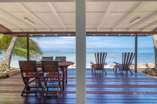 a porch with chairs and a table and the ocean at Fare Matairoa - 2BR Beach Cottage in Iumaru