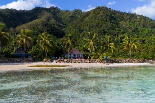 a beach with palm trees and a group of chairs at Fare Matairoa - 2BR Beach Cottage in Iumaru