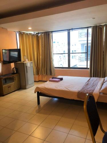 a bedroom with a bed and a tv and a large window at จอมเทียน ซีไซด์ เกสเฮ้าส์ in Jomtien Beach