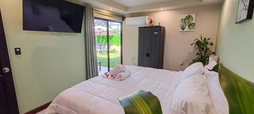 a bedroom with a white bed and a window at Arenal Jendrik house in Agua Azul