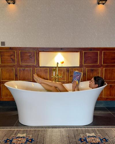 a woman laying in a bath tub reading a book at Willing Resort, Trongsa in Kagha