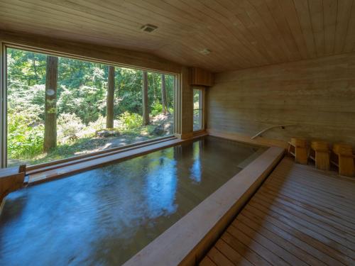 a swimming pool in a wooden house with a window at Wanosato in Takayama