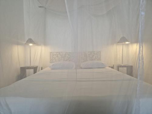 a white bedroom with a large white bed with two pillows at CocoVilla Boutique Resort in Beruwala