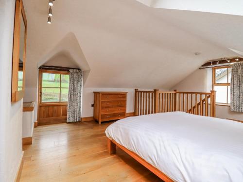 a bedroom with a white bed and a wooden floor at Briws in Llangwm