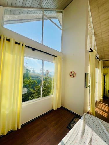 a bedroom with a large window with yellow curtains at Moon Mist Villa in Kotagala