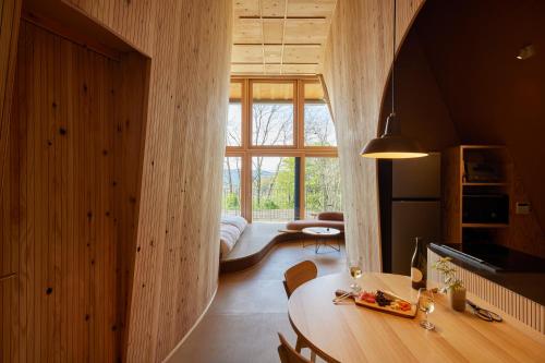 a living room with a table and a large window at SANU 2nd Home 軽井沢1st in Oiwake