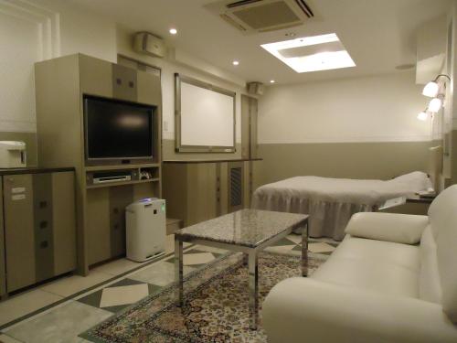 a hospital room with a tv and a couch and a table at ホテル アイアンプレミアム 六甲店 Adult only男塾ホテルグループ in Kobe