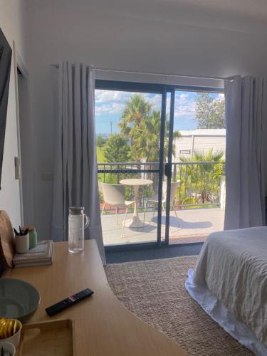 a bedroom with a bed and a view of a patio at Corrigans Beach Escape Studio in Batehaven