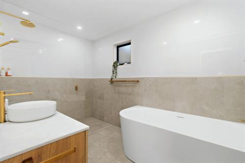 a bathroom with a white tub and a sink at Portside at The Arc by Experience Jervis Bay in Vincentia