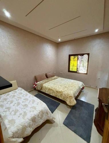 two beds in a room with two rugs at Ferme agafay in El Karia