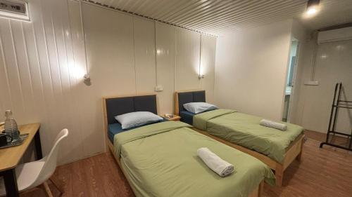 two beds in a room with a table and a desk at 5 Minutes Away Airport Lodge in Putatan