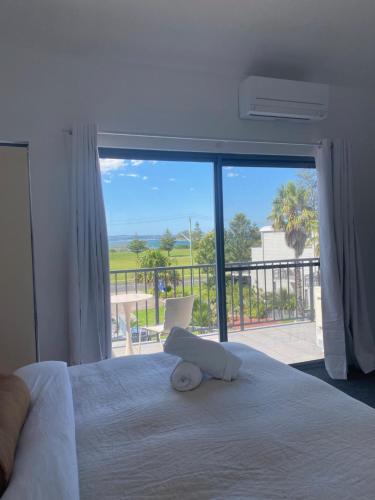 a bedroom with a bed with a view of a balcony at Corrigans Beach Escape 1 Bedroom Apartment in Batemans Bay