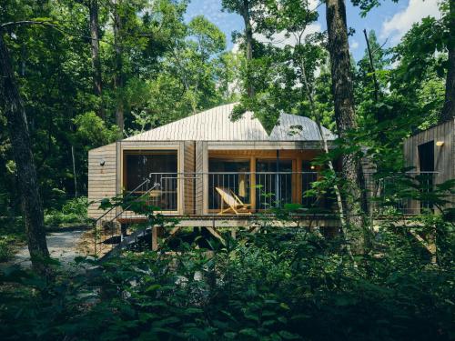 a cabin in the woods with a deck and trees at SANU 2nd Home 白馬 1st in Hakuba