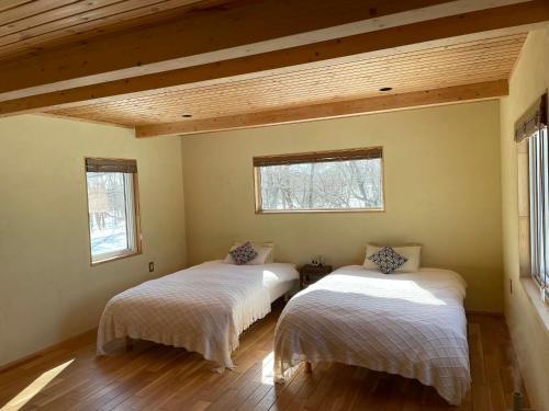 two beds in a room with two windows at 小さな森の貸し切り宿Forest-House-Ranapirica in Shibetsu