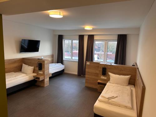 a room with two beds and a flat screen tv at Hotel am Pferdemarkt in Aurich