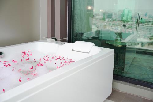 a bathroom with a white tub with red confetti at Valia Bangkok Sukhumvit 24 by Kingston Hotels in Bangkok