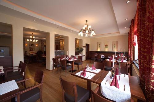 a restaurant with tables and chairs and a chandelier at Hotel Pfeffermühle in Borchen