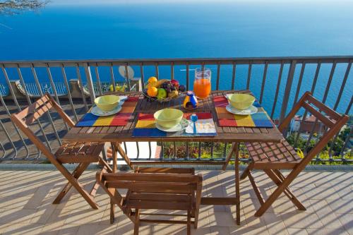 a wooden table with a bowl of fruit on a balcony at Calipso Residence in Furore