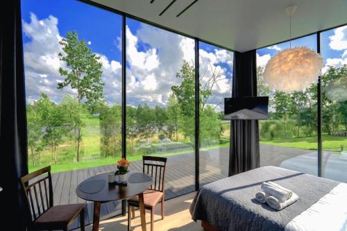 a bedroom with a bed and a table and a large window at Pulli Country Club - Private Sauna & River View in Pärnu