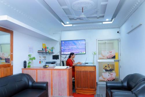 a woman sitting at a desk in a room with a computer at Sun Shine Resort & Spa in Kovalam
