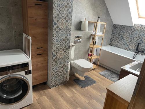 a bathroom with a toilet and a washing machine at Beskid Penthouse Milówka in Milówka