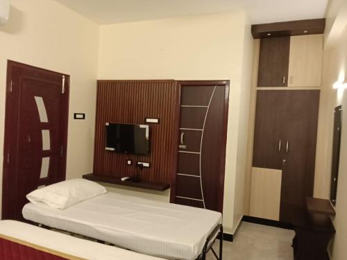 a small bedroom with a bed and a television at Tamil Homestay in Thanjāvūr