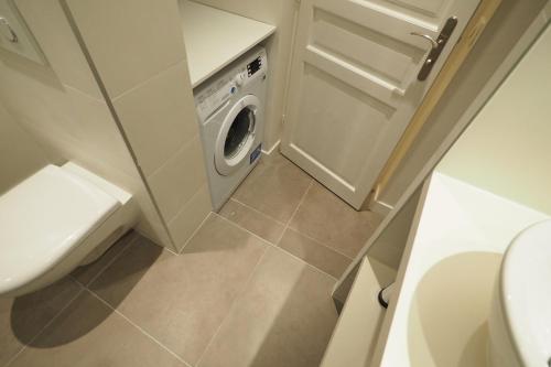 une petite salle de bains avec un lave-linge. dans l'établissement Louvre Opera Private ChicSuites, à Paris