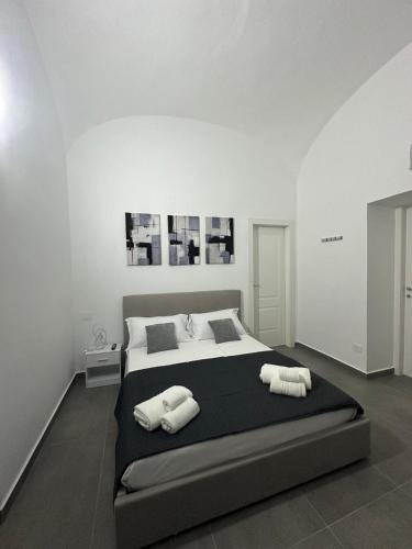 a white bedroom with a large bed with two towels at Dimora del Corso in Caserta