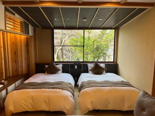 two beds in a room with a window at Tatsumikan in Minakami