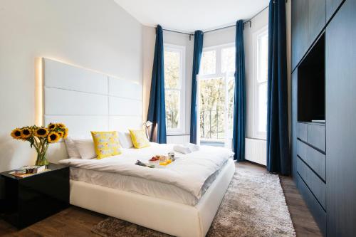 ロンドンにあるKensington Garden View Apartmentのベッドルーム(青いカーテン、テレビ付)