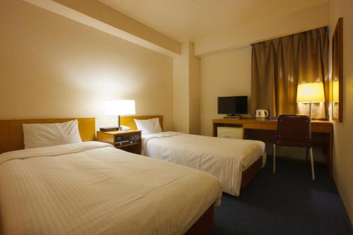 a hotel room with two beds and a desk at Sankei City Hotel Hachioji in Hachioji