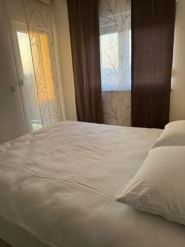 a white bed in a room with a window at White Horizon Apartment in Teslić