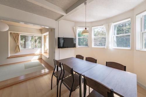 a dining room with a table and chairs and windows at Shakunagedaira Rental cottage - Vacation STAY 18459v in Numanokura