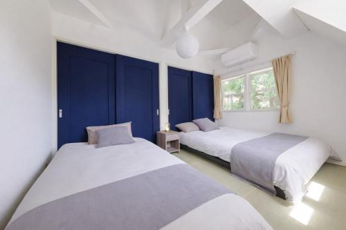 two beds in a room with blue walls at Shakunagedaira Rental cottage - Vacation STAY 18459v in Numanokura