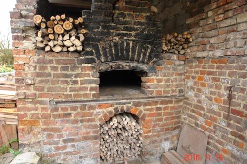 a brick oven with a pile of fire wood at La Petite Maison in Sart lez Walhain