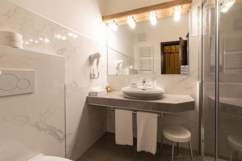a white bathroom with a sink and a shower at G. Hotel Des Alpes (Classic since 1912) in San Martino di Castrozza