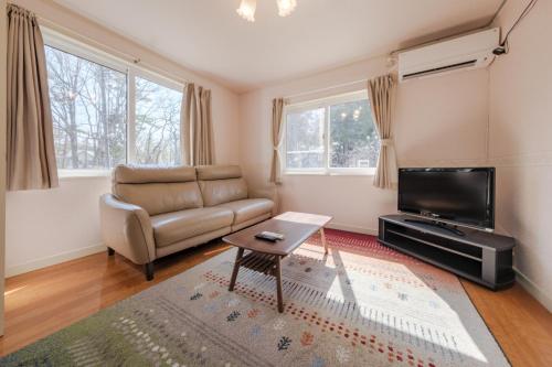a living room with a couch and a tv at Shakunagedaira Rental cottage - Vacation STAY 18463v in Numanokura