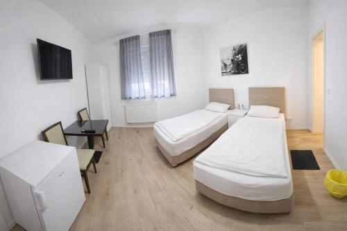 a room with two beds and a desk and a tv at Monteurzimmer deSoL in Forst