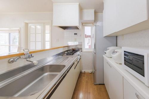 a white kitchen with a sink and a refrigerator at Shakunagedaira Rental cottage - Vacation STAY 18464v in Numanokura