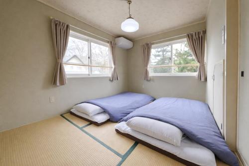 two beds in a bedroom with two windows at Shakunagedaira Rental cottage - Vacation STAY 18464v in Numanokura