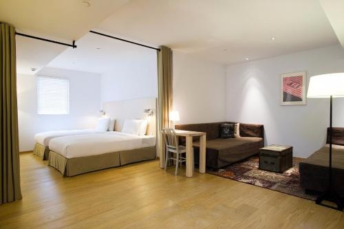 a hotel room with two beds and a couch at amba Taipei Ximending in Taipei