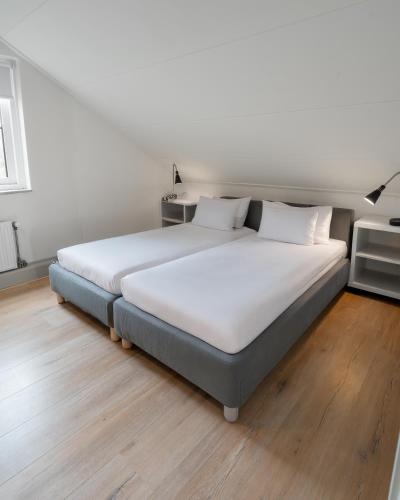 a large white bed in a room with wooden floors at Spaanse Galeien 16 in Retranchement