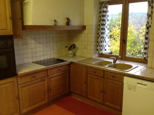 uma cozinha com armários de madeira, um lavatório e uma janela em Les 23 Mûriers em Chauzon