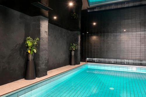 a swimming pool with two potted plants in a room at Hotel des Carmes in Aurillac